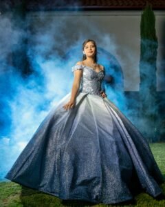 Captured moment of a young woman in a stunning blue quinceañera gown outdoors, exuding elegance and youth.